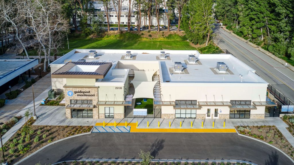 Exterior view of a Guidepost Montessori school building with landscaped entry, modern architecture, and outdoor play courtyard.