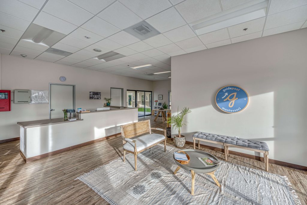 Guidepost Montessori school lobby with natural light, modern furnishings, and the Guidepost Montessori logo on the wall.
