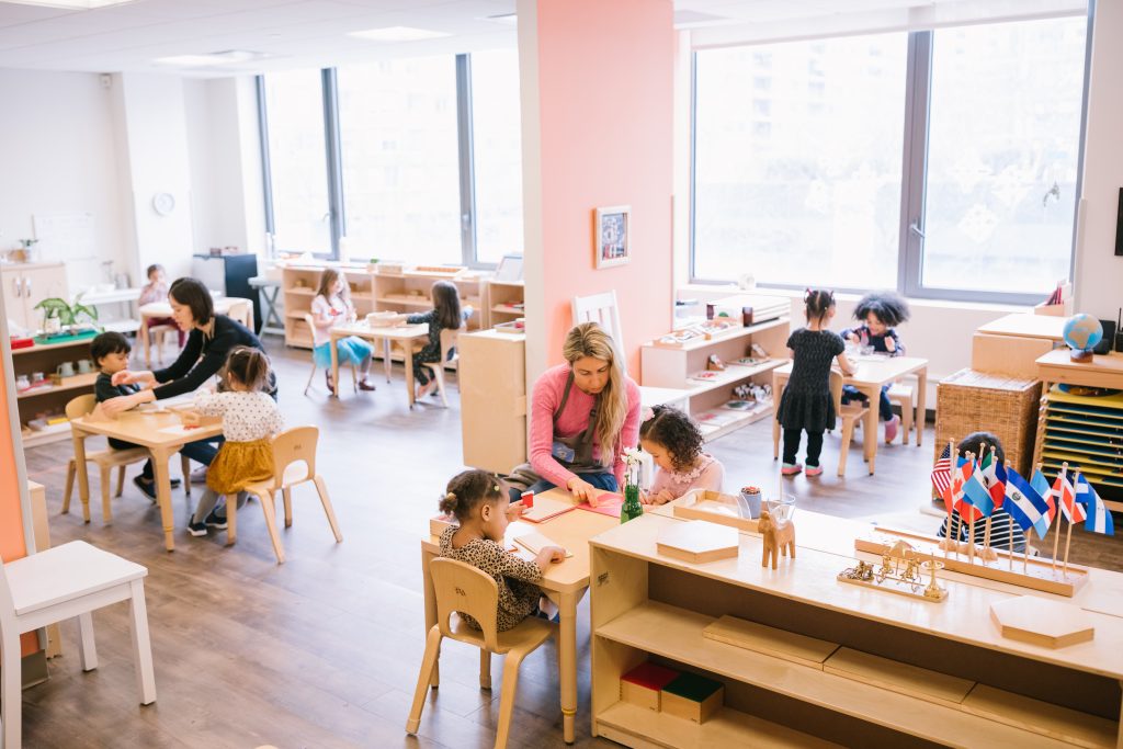 Guidepost Montessori classroom with multiple children working at individual tables across different activities.