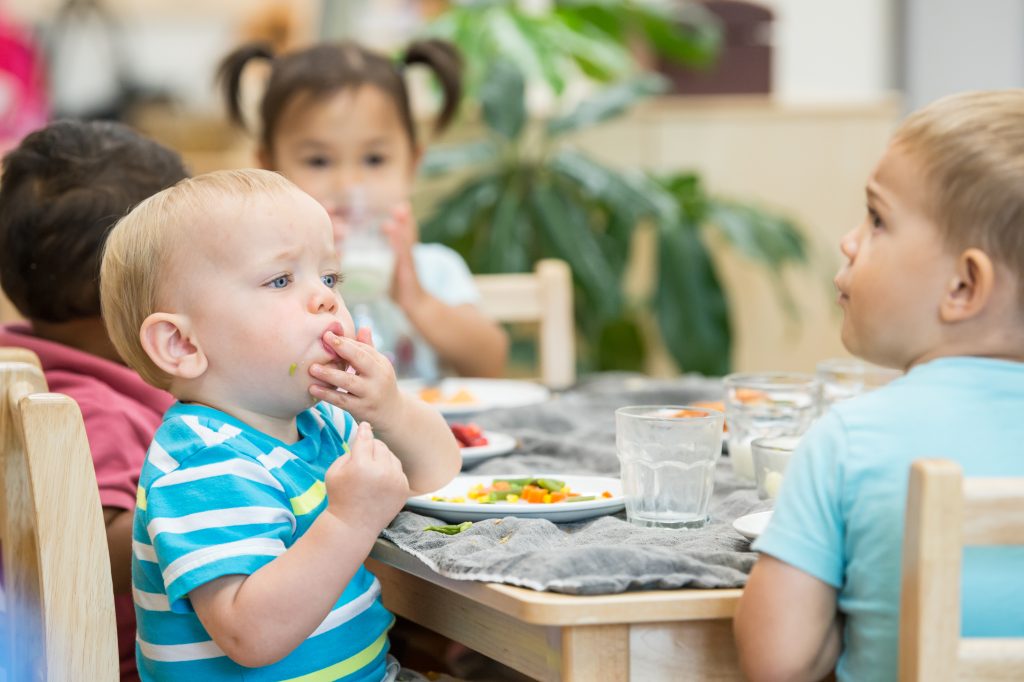 Children eat independently at small tables in a Montessori classroom, maintaining calm routines during the holiday season.