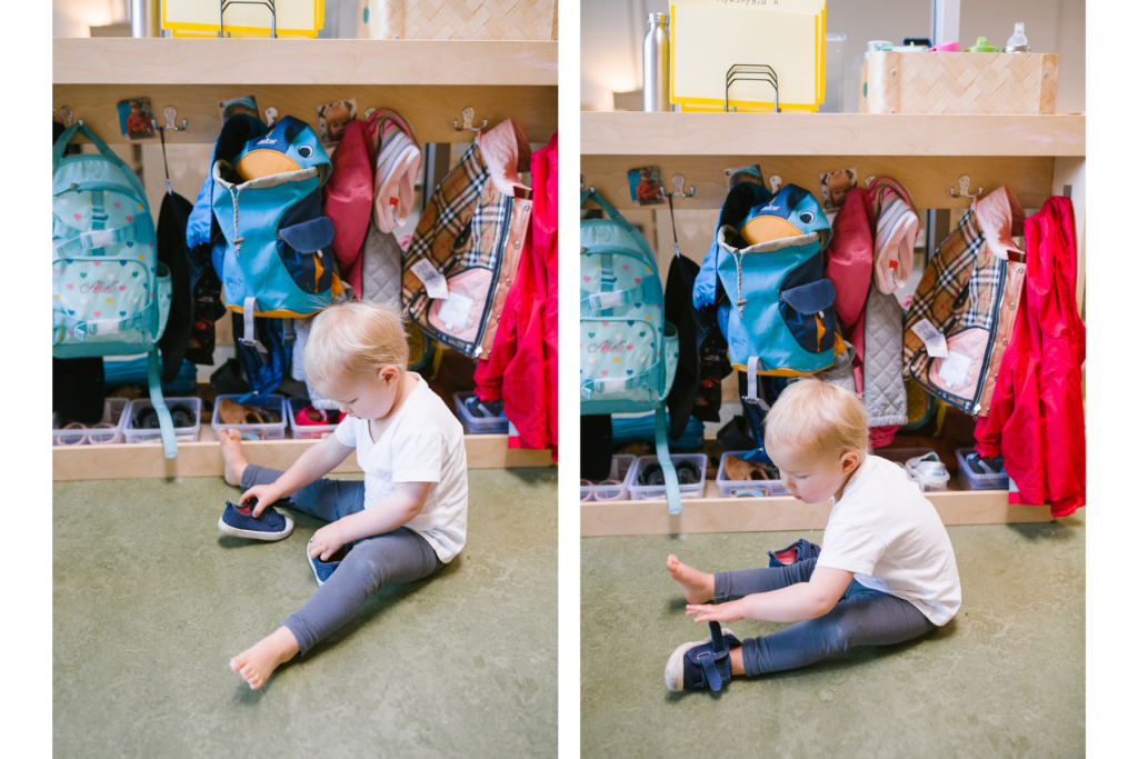 Toddler sitting on the floor putting on his own shoes in a Montessori classroom cubby area.